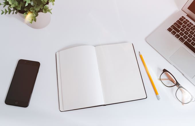 Notebook and laptop on a desk for writing a project brief